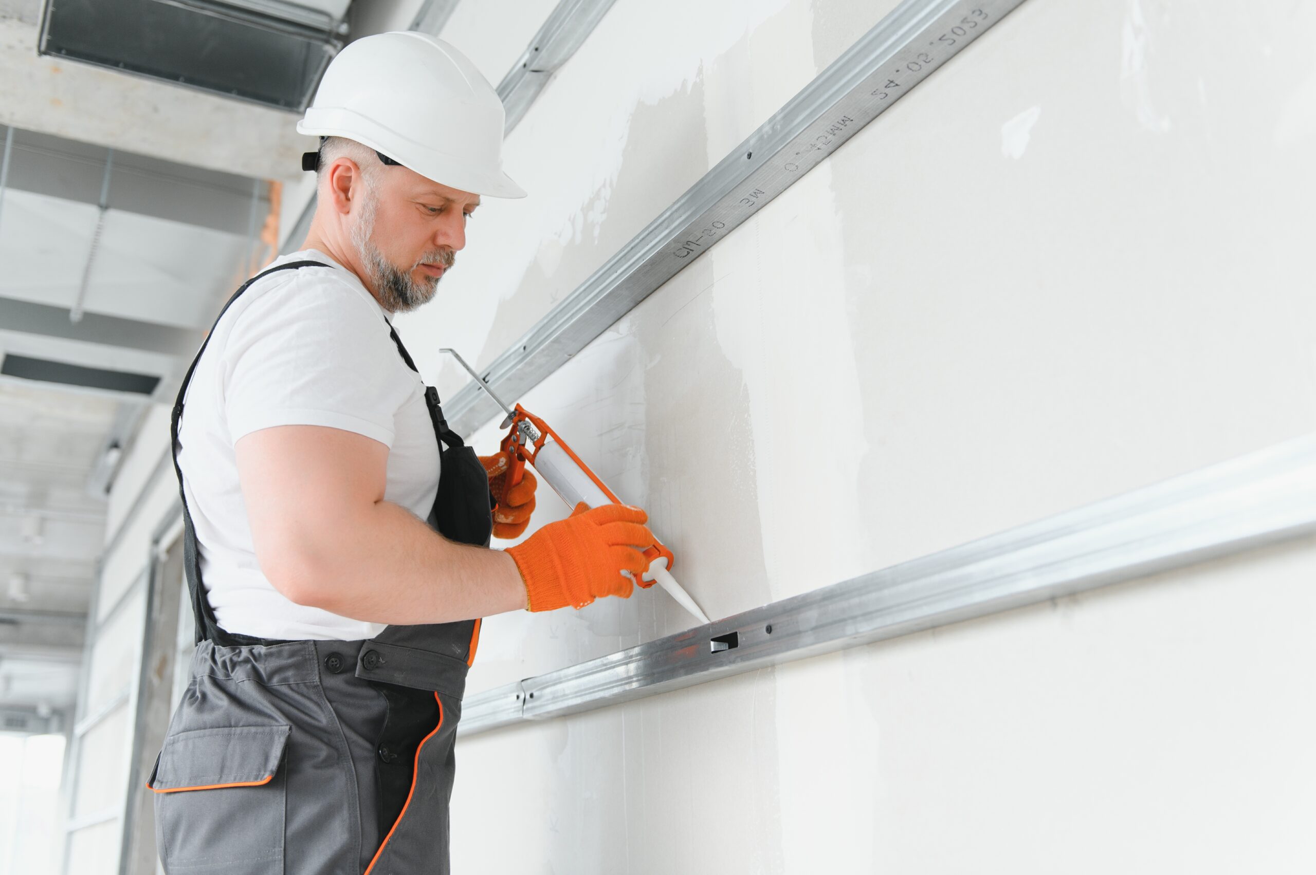 Builder sealing drywall seams with silicone gun
